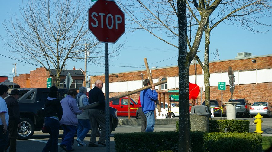 The Christian faithful walking on the sidewalk and carrying a cross in downtown Puyallup, Washington.